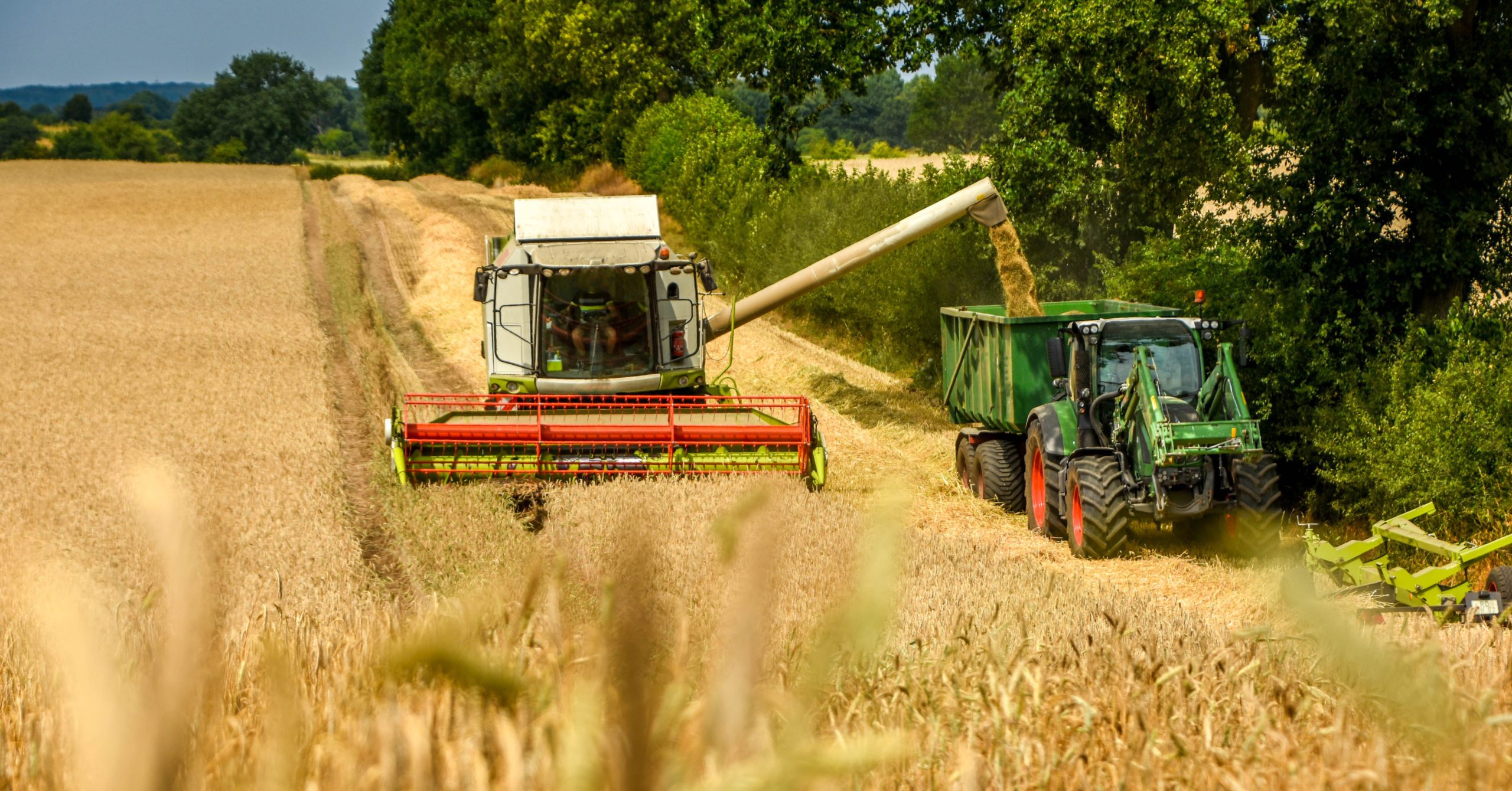 Combine harvester and tractor working in a field